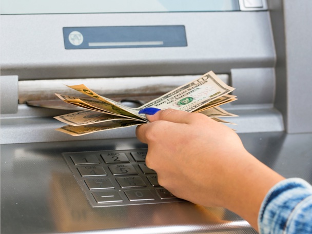 Hand taking bills from an ATM machine